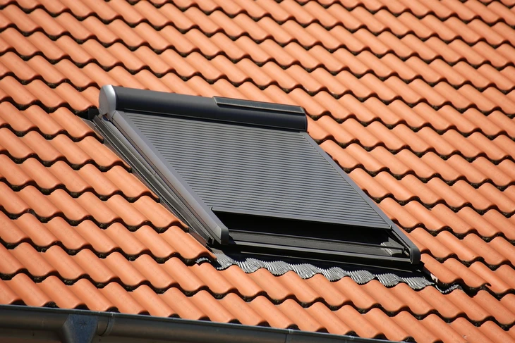 Deux ouvriers du toit en uniforme de protection portent et gants, à l'aide d'un pistolet à ongles pneumatique ou d'un pistolet pneumatique et installent des tuiles en béton sur le toit du nouveau toit, Concept de bâtiment résidentiel en construction