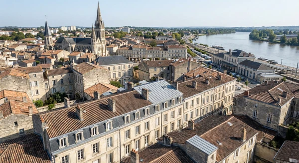 Une vue a&eacute;rienne ou perspective de la ville de Libourne montrant son tissu urbain avec b&acirc;timents r&eacute;sidentiels et patrimoniaux caract&eacute;ristiques, ou une image de la gare de Libourne avec ses abords urbains, illustrant ainsi le territoire d'intervention de l'entreprise en Gironde