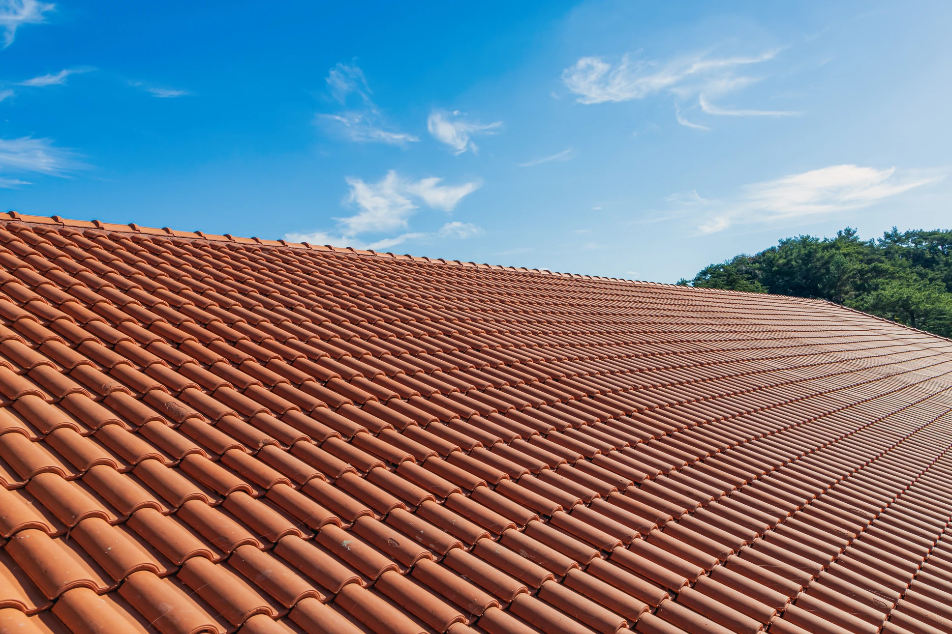 Extérieur d'une maison contemporaine avec toiture en tuiles mécaniques brunes et bardage bois horizontal de teinte orangée