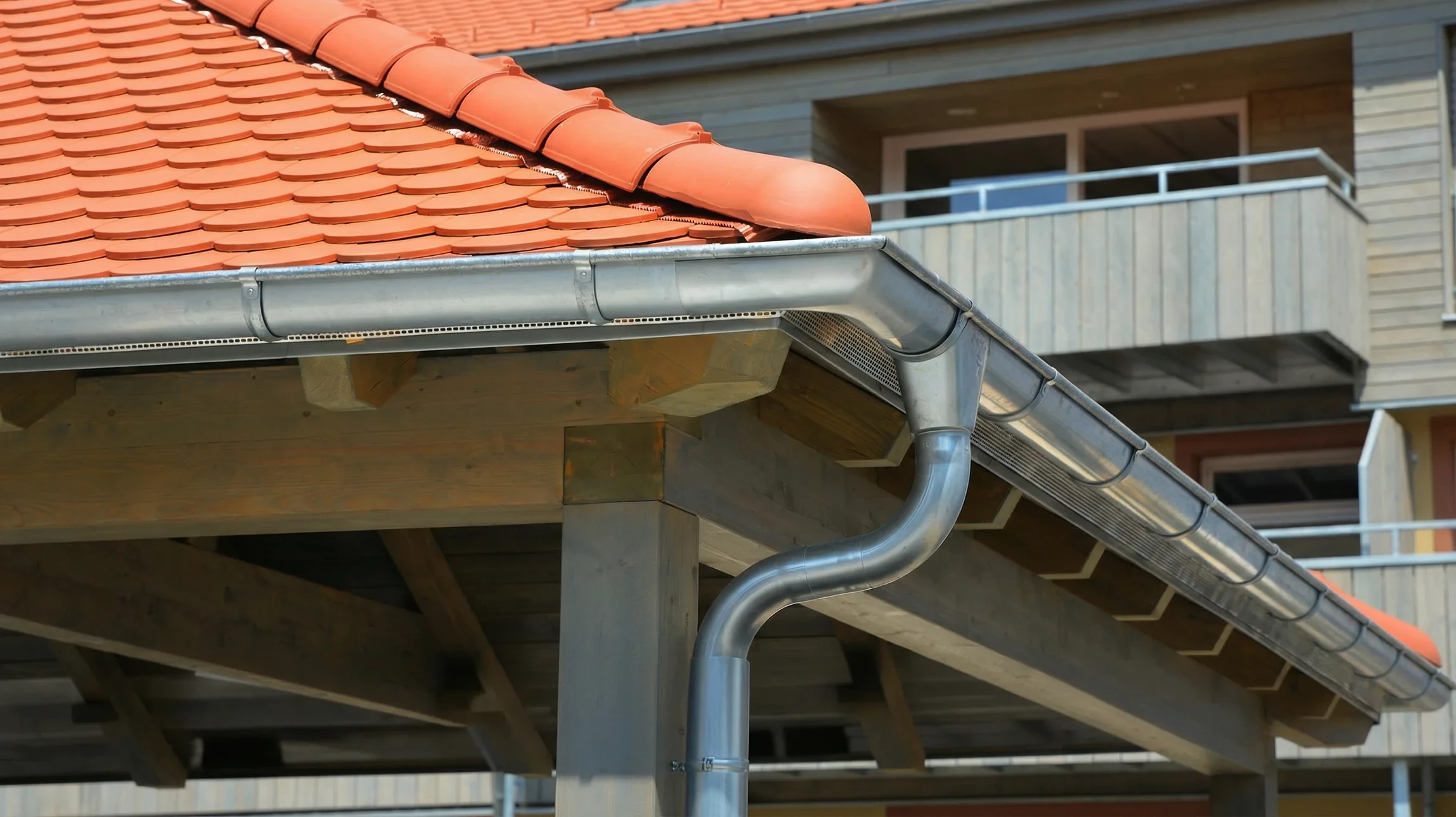 Ouvrier en bleu de travail avec casque blanc installe une gouttière en aluminium sur une maison résidentielle